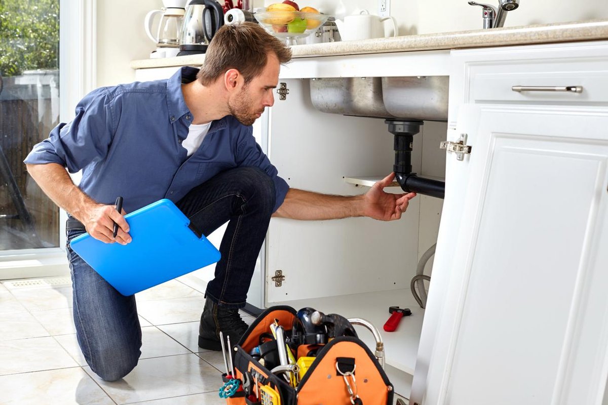 Professional plumber working under sink